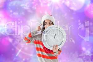 Composite image of thoughtful brunette holding a clock