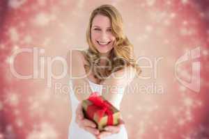 Composite image of smiling blonde offering a small gift