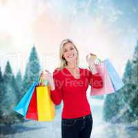 Composite image of happy blonde holding shopping bags