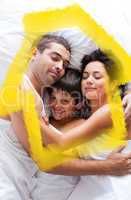 Composite image of happy family lying in bed
