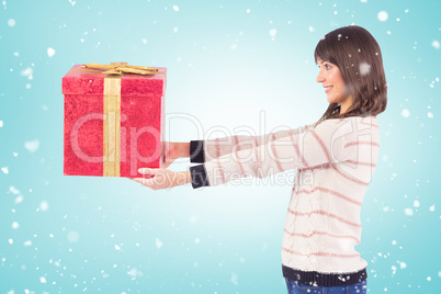 Composite image of cute young woman holding a gift