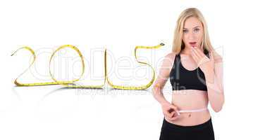 Composite image of fit young blonde looking at measuring tape