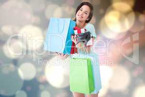 Composite image of happy brunette with shopping bags and gifts