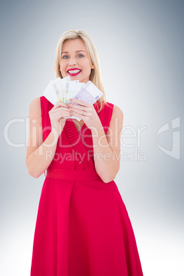 Stylish blonde in red dress holding cash