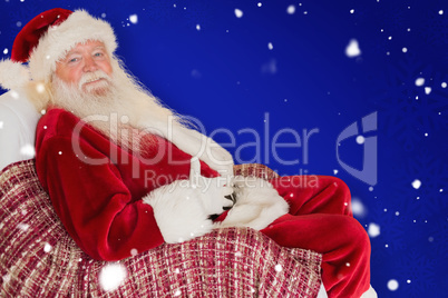 Composite image of santa holding his belly on the armchair