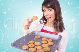 Composite image of festive brunette showing hot cookies
