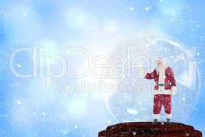 Composite image of santa presenting in a snow globe