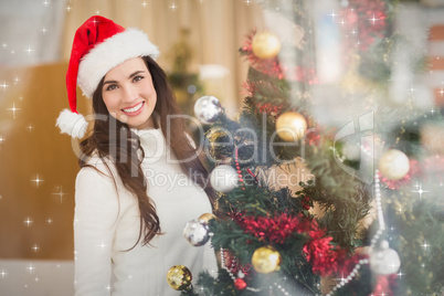 Composite image of smiling brunette decorating a christmas tree