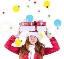 Composite image of festive redhead holding pile of gifts