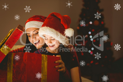 Composite image of festive mother and daughter opening a christm