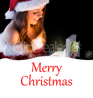 Composite image of pretty brunette in santa outfit opening gift