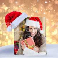 Composite image of festive brunette pressing gift at christmas
