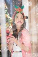 Composite image of smiling brunette in christmas hat holding mug
