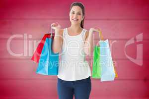 Composite image of cheerful brown hair holding shopping bags