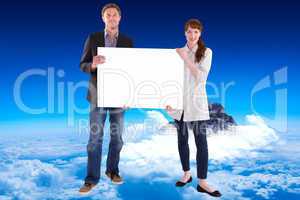 Composite image of smiling couple holding large sign