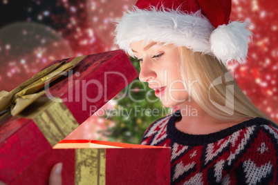 Composite image of festive blonde opening a gift