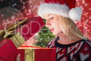 Composite image of festive blonde opening a gift