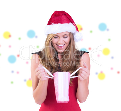 Composite image of festive blonde opening a gift bag