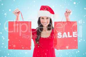 Composite image of festive brunette holding sale bags