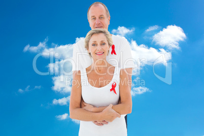 Composite image of mature couple supporting aids awareness toget
