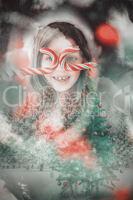 Composite image of happy little girl in santa hat holding candy