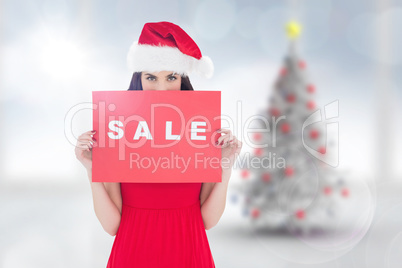 Composite image of brunette in red dress holding sale sign