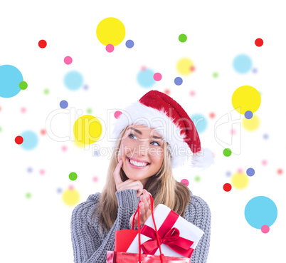 Composite image of festive blonde holding christmas gift and bag