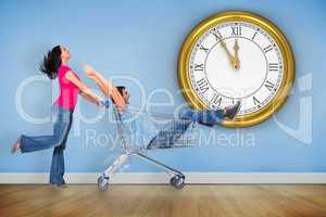 Composite image of young couple having fun with shopping cart