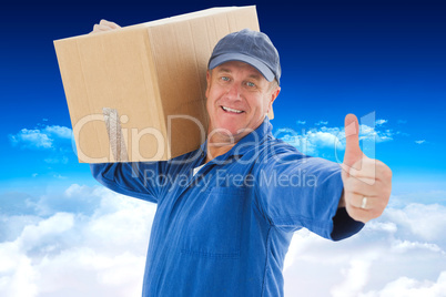 Composite image of happy delivery man holding cardboard box