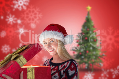 Composite image of festive blonde opening a gift