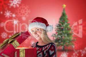 Composite image of festive blonde opening a gift