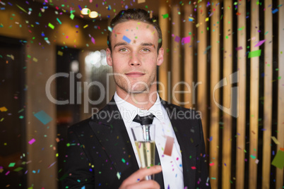 Composite image of handsome man holding flute of champagne