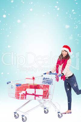 Composite image of cute woman in santa hat with shopping trolley