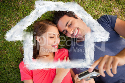 Composite image of two smiling friends looking at photos on a ca