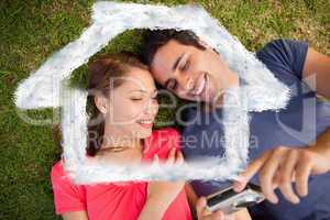 Composite image of two smiling friends looking at photos on a ca