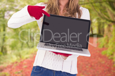 Composite image of festive blonde pointing to laptop