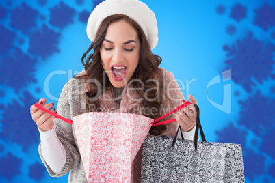 Composite image of surprised brunette looking in shopping bag