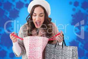 Composite image of surprised brunette looking in shopping bag