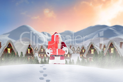 Composite image of santa carrying gifts in the snow