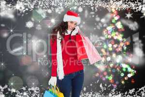 Composite image of happy brunette in winter wear holding shoppin