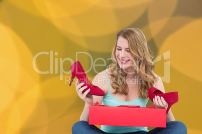Composite image of blonde woman discovering shoes in a gift box