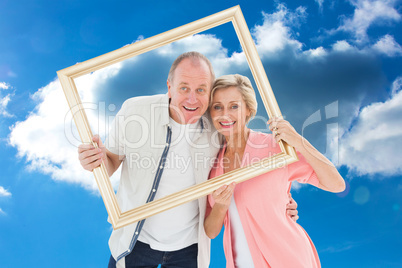 Composite image of older couple smiling at camera through pictur