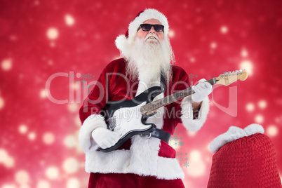 Composite image of santa claus plays guitar with sunglasses