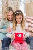 Composite image of daughter opening christmas gift with mother