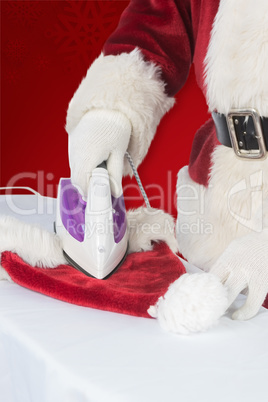 Composite image of father christmas is ironing his hat