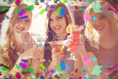 Composite image of attractive friends drinking cocktails togethe