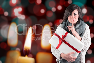 Composite image of brunette holding gift and keeping a secret