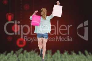 Composite image of rear view of young woman with shopping bags