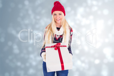 Composite image of festive blonde holding a gift