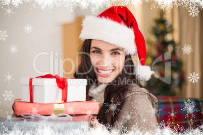 Composite image of festive brunette holding pile of gifts at chr